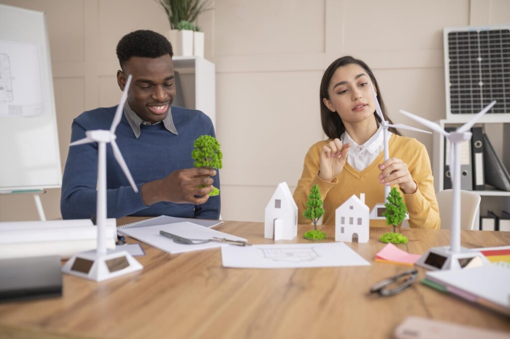 Un homme et une femme travaillent sur une maquette d'éoliennes dans un bureau, en soulignant le mot-clé « RSE ».