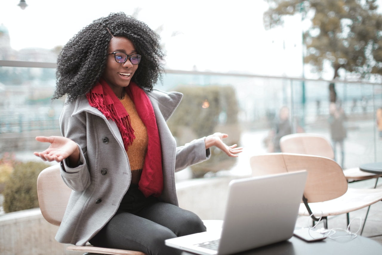 Une jeune femme noire assise sur un banc avec son ordinateur portable en Guadeloupe.